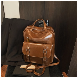 Macro shot of brown retro PU leather backpack with dual buckle flap and glossy finish