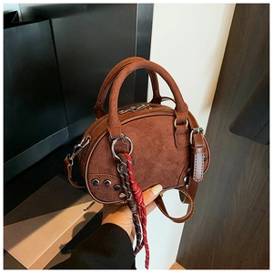 Detail of brown suede crossbody bag featuring silver rivets and braided cord zipper pull