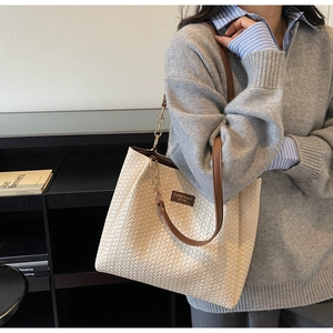 Détail du sac cabas tissé avec bandoulière en cuir et chaîne en métal doré élégante