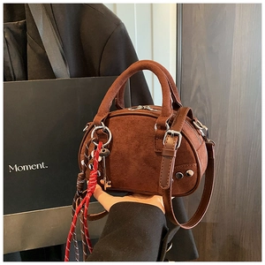 Detail of dark brown suede boston bag with silver studs and braided key pendant