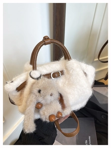 Detail einer weißen Kunstfell-Handtasche mit braunem Lederriemen und Plüschhasen