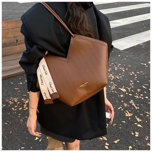 Detail showing the herringbone embossed texture and V-shaped cut on a brown tote bag