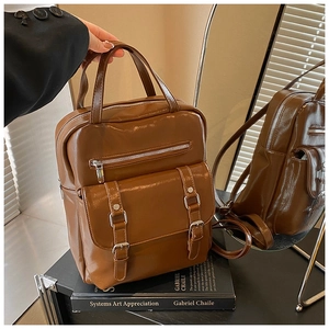 Detail of vintage dark brown polished PU leather backpack on books with mirror reflection