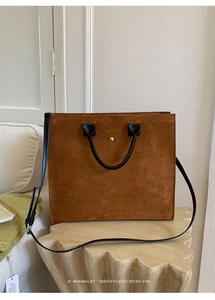 Dettaglio della borsa tote in pelle scamosciata caramello con manico nero e rivetto