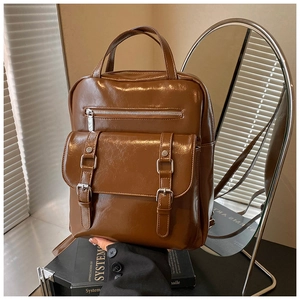 Close-up of brown vintage leather backpack with silver zippers and buckle pockets