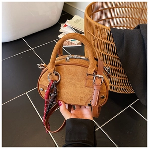 Brown suede handbag detail with silver rivets and bicolor braided decorative cord
