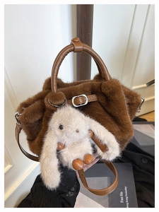 Detail einer braunen Kunstpelz-Handtasche mit weißem Hasenanhänger und Ledergriff