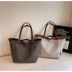 Detailed shot of large canvas tote bags with leather handles and side brand labels