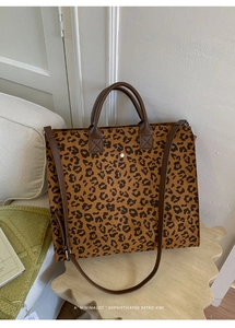 Dettaglio della borsa tote leopardata con manici in pelle marrone su uno sgabello