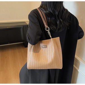 Detail view of woven brown tote bag featuring gold chain strap and textured leather finish