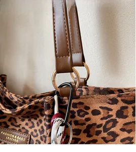 Dettaglio della borsa in tela leopardata con hardware dorato e cinturino intrecciato