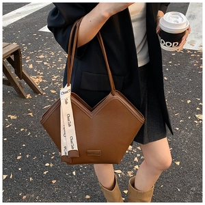 Brown herringbone tote bag worn over the shoulder by a model in a black suit jacket
