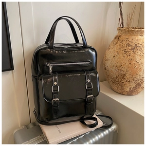 Detail of glossy black vintage backpack on luggage with hand strap and buckle straps