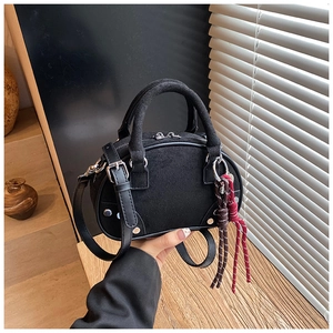 Detail of black suede crossbody bag with silver hardware and braided rope charm