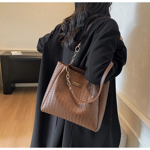 Close-up of brown woven leather texture and elegant gold chain strap on the tote bag