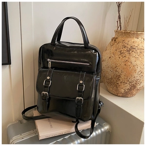 Close-up of black glossy backpack with silver metal buckles and adjustable straps