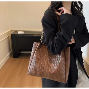 Détail du sac cabas en cuir tressé avec bandoulière chaîne et texture luxueuse