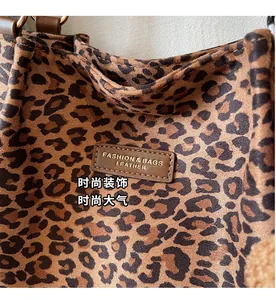 Dettaglio della texture scamosciata leopardata e logo in pelle su borsa tote retro