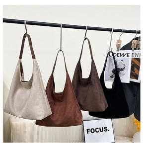Detail view of four minimalist suede tote bags in various colors with leather handles