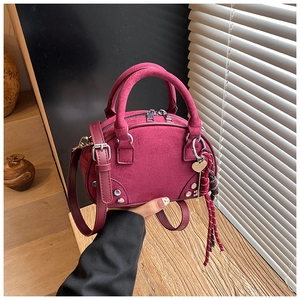 Detailed macro shot of suede crossbody bag texture with heart pendant and rivet details