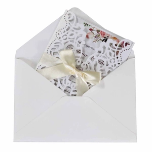 Laser cut wedding invitation with white floral cover, pink insert, and silk bow knot