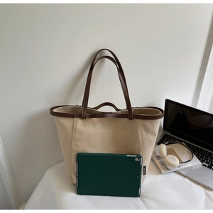Detail view of spacious beige canvas tote bag holding a green tablet for size reference