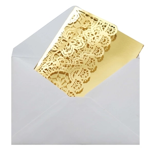 Macro shot of gold laser-cut lace floral pattern on cream wedding invitation envelope