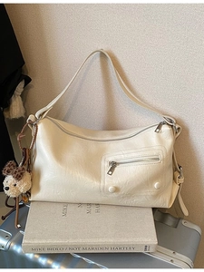 Elegant cream-colored faux leather shoulder bag with plush puppy charm and front zipper detail