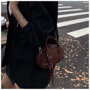 Detail view of a brown suede Boston bag with silver studs and silk scarf on a model