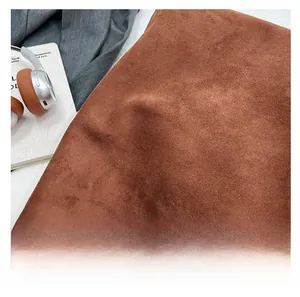 Detailed macro view showing the soft texture of brown suede fabric on a tote bag