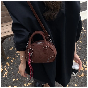 Street style view of a brown suede mini Boston bag with silver rivet details on the base