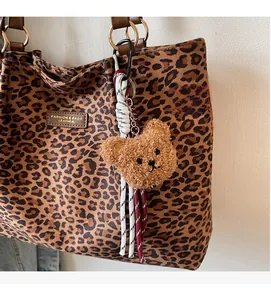 Dettaglio charm orsetto di peluche con corda intrecciata su borsa leopardata