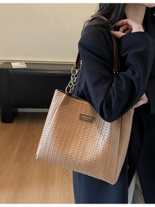 Sac fourre-tout en cuir tressé marron avec bandoulière chaîne porté par un mannequin
