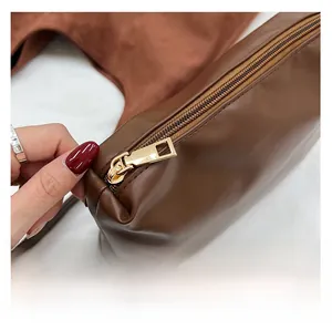 Close-up of a smooth golden metal zipper detail on a dark brown faux leather tote bag