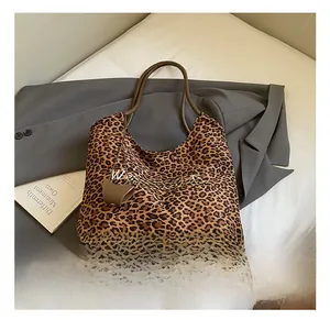Detail of leopard print tote bag with brown leather handles and a heart charm