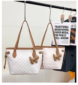 Detail of white tote bags with woven texture, leather dog charms and drawstrings