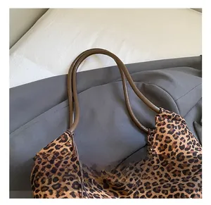 Close-up of leopard print canvas tote bag featuring a sturdy brown rounded top handle