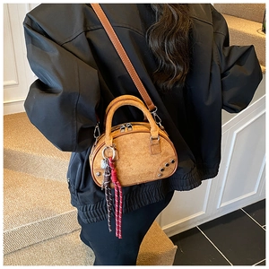 Brown suede crossbody bag worn by a model in a minimalist modern interior setting