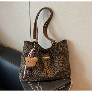 Dettaglio della borsa tote scamosciata leopardata con manici in pelle e ciondolo orsetto