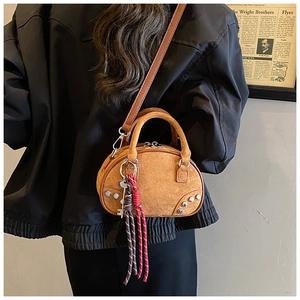 Detail of caramel brown suede round crossbody bag with silver studs and braided keychain