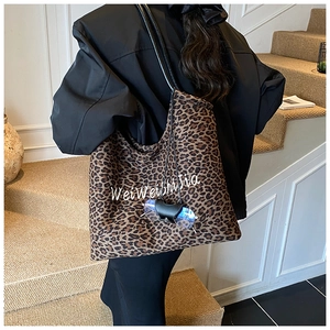 Detail of leopard print tote bag with stylish white script text and black straps