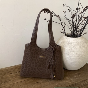 Detailed close-up of dark leopard print tote bag with metal logo and elegant leather ties