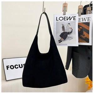 Detail of minimalist black suede tote bag with seamless shoulder strap in a stylish setting
