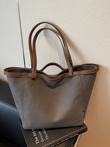 Large grey canvas tote bag with brown leather handles and spacious minimalist design