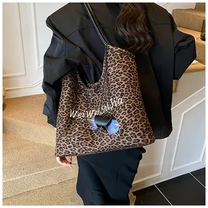 Detail view of large leopard print tote bag with black straps and decorative sunglasses