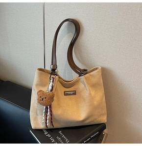 Detail of khaki suede tote bag with leather straps and a cute plush bear charm