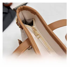 Close-up of golden metal zipper and brown leather trim on a woven tote bag