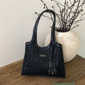 Detail of black leopard print tote bag in suede fabric with a gold fashion logo plate