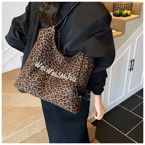 Macro shot of stylish leopard print tote bag with white cursive brand embroidery detail