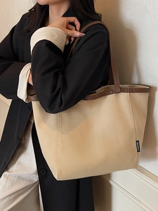 Minimalist large canvas tote bag with brown leather handles worn over the shoulder